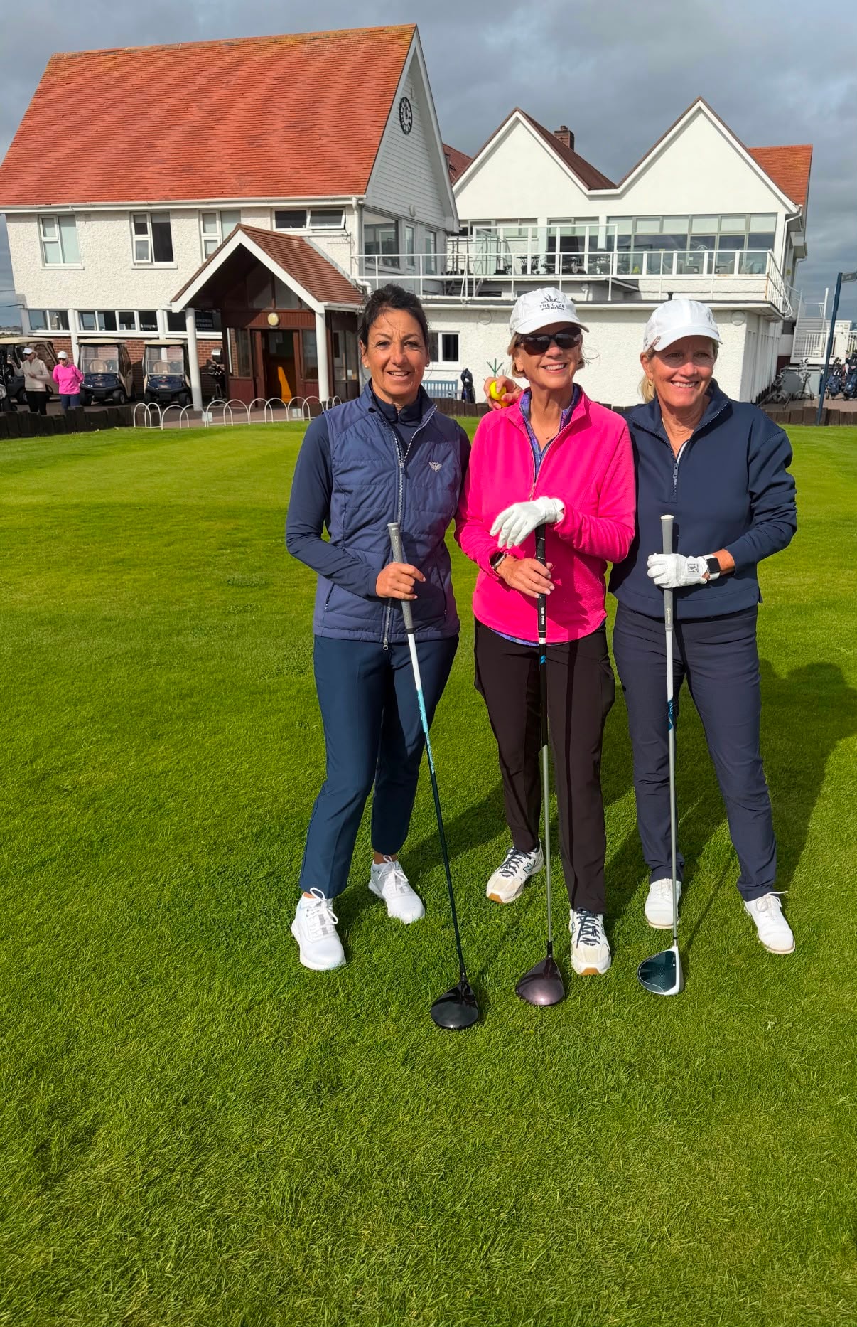 Three Wild Dunes LGA ladies posing with clubs at a scenic coastal golf course