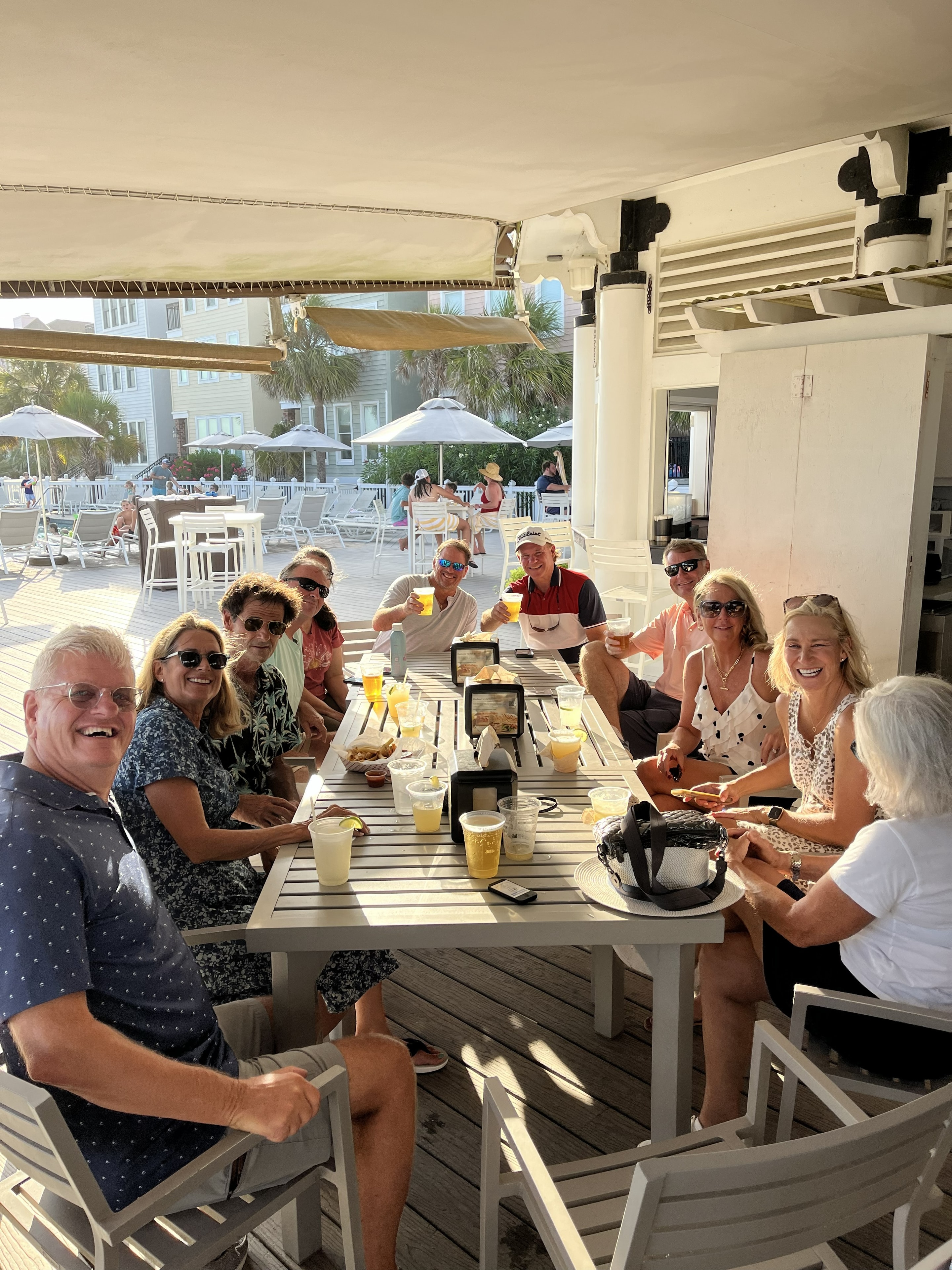 Wild Dunes members gathered at an outdoor beachside venue enjoying drinks together