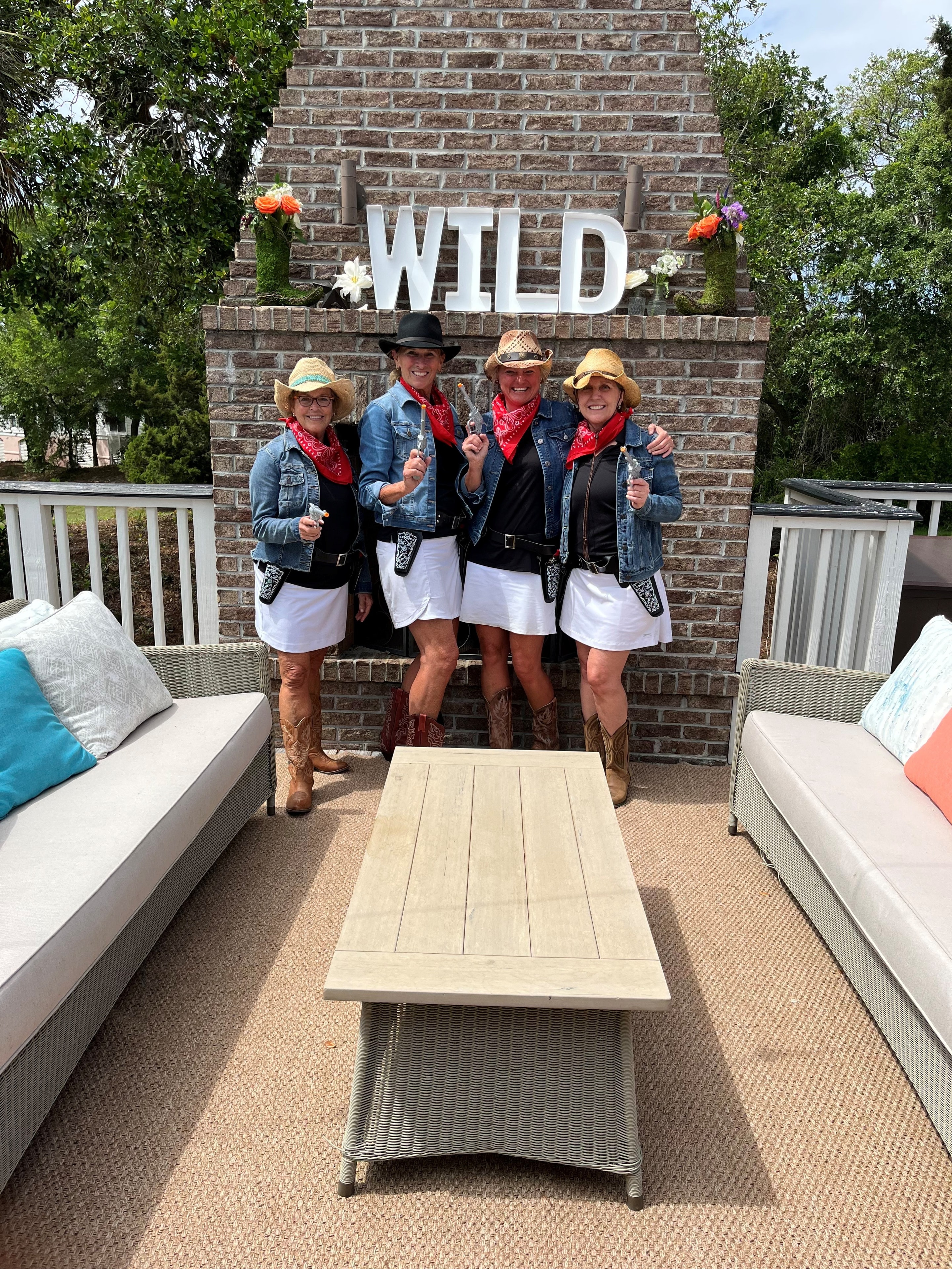 Four Wild Dunes LGA ladies dressed as cowgirls in front of the WILD sign on the deck
