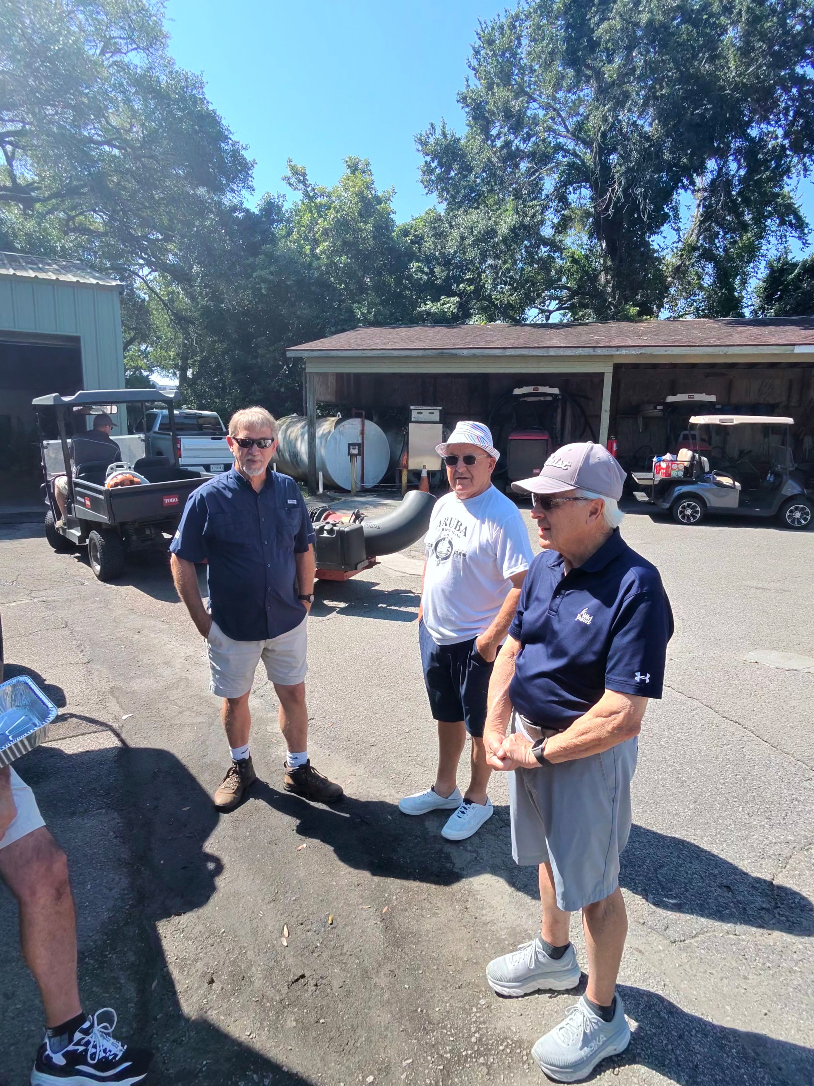 Wild Dunes members chatting by the maintenance shed after a round